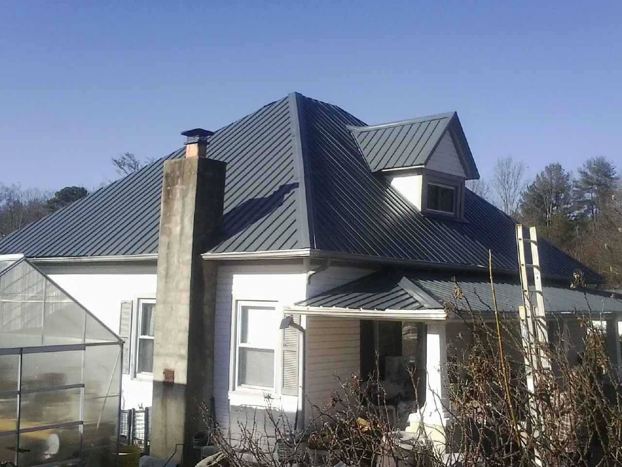 Dark blue standing seam metal roof on a white farmhouse with dormer — Slate & Tile Roof Repair by Roofing Brothers in Marlborough