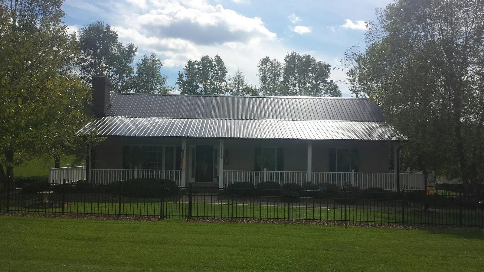 Gray metal roof on a brick ranch with a full width front porch — Gutter Guard Installation work by our crew in Marlborough
