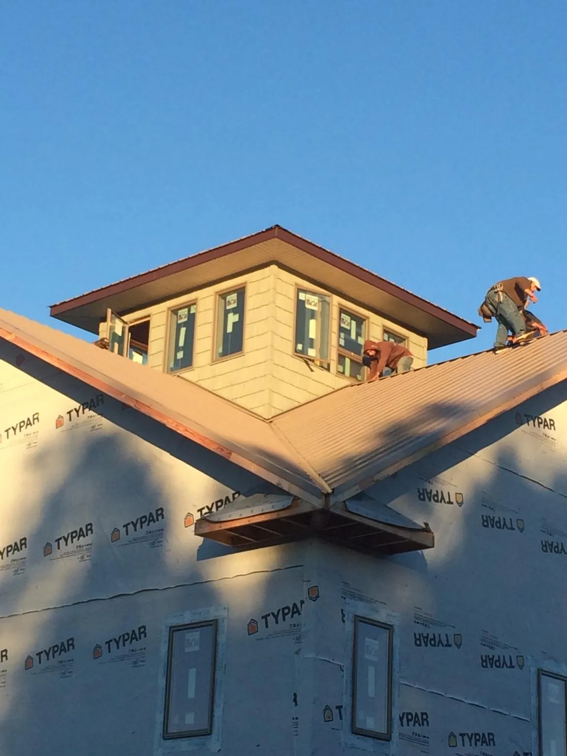 Roofers working around a rooftop cupola on a new metal roof at sunset — Roof Waterproofing in Marlborough by Roofing Brothers
